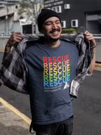 Navy Blue Tshirt “Rescue – Because They Can’t Save Themselves” rainbow animal rescue shirt, standing outdoors in the city. This colorful cat and dog rescue T-shirt promotes TNR, fostering, and animal rescue awareness — perfect for volunteers and compassionate pet lovers.