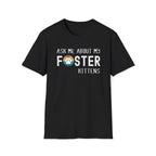 Black soft t-shirt with text that reads ‘Ask Me About My Foster Kittens’ and a retro styled rainbow paw-print graphic in the word Foster