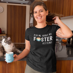Woman in a kitchen wearing a black t-shirt with 'Ask me about my foster kittens and a rainbow paw-print graphic in the word Foster