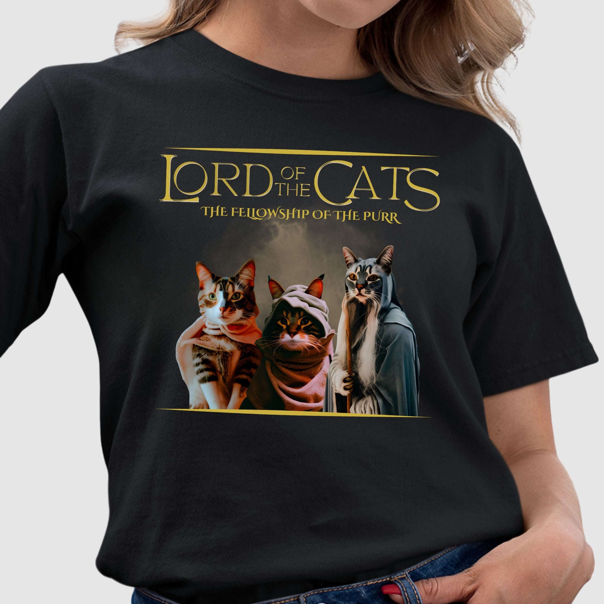 Black t-shirt featuring three cats dressed in fantasy-style cloaks with text ‘Lord of the Cats – The Fellowship of the Purr.’ Movie Parody. Soft 100% ringspun cotton cat lover shirt
