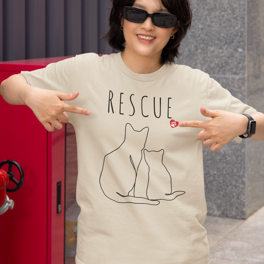 woman pointing to her Natural Rescue Minimalist Line Art tee shirt with Cat and Kitten and a little red heart with a white paw print inside. 