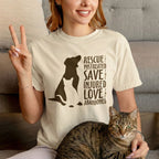 Woman wearing a natural colored tshirt that reads in bold chocolate brown print Rescue The Mistreated Save the Injured Love the Abandoned featuring a dog and cat image appealing to animal rescue, dog rescue, cat rescue, tnr advocates or animal lovers. Cat mom sitting holding up two fingers in peace sign and brown tabby cat sitting on her lap.