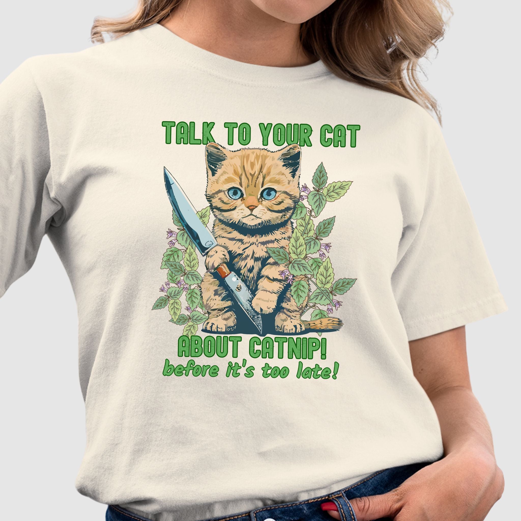 Beige t-shirt with a cute kitten holding a knife surrounded by catnip leaves and the text ‘Talk to Your Cat About Catnip Before It’s Too Late.’ Funny cat lover shirt 