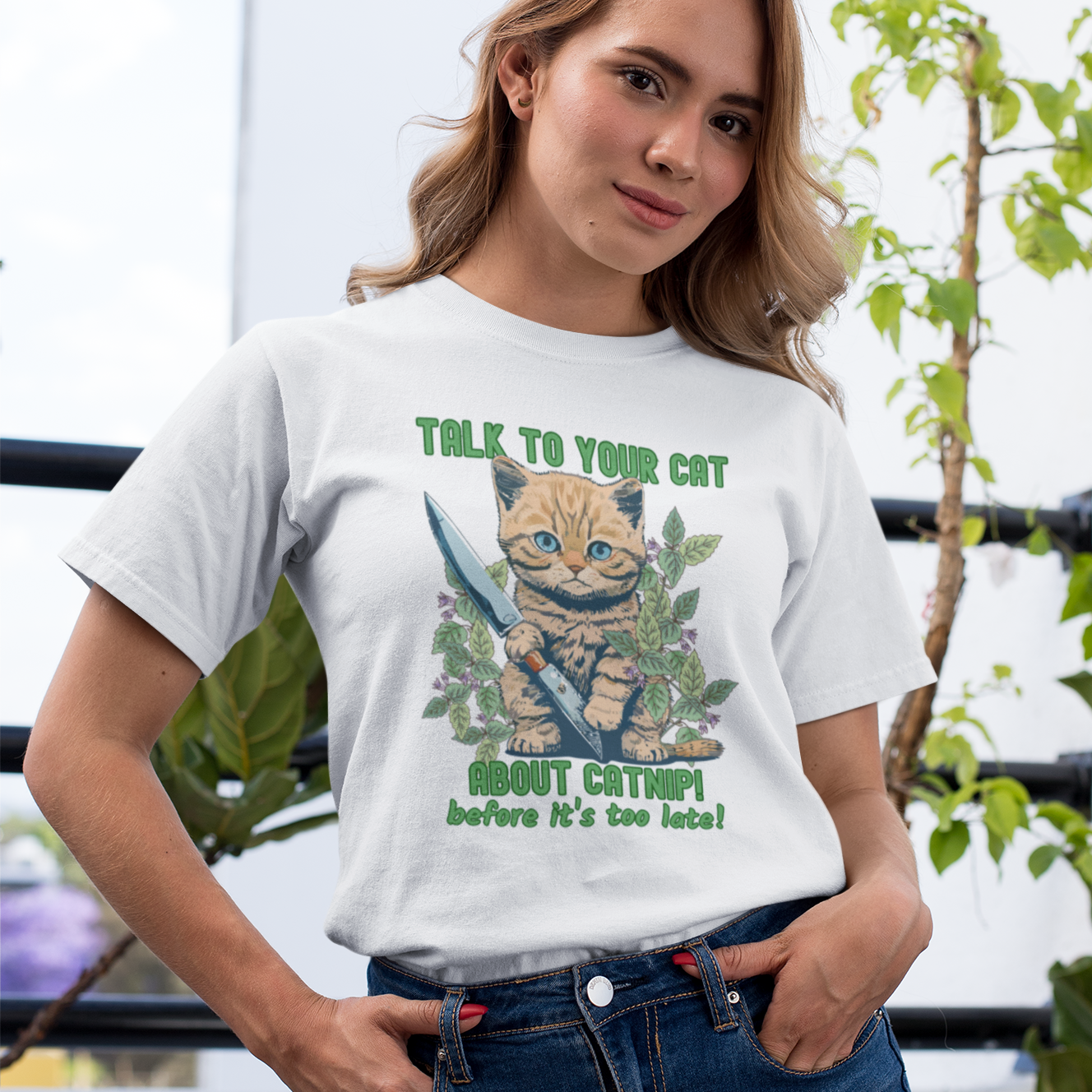 Beige t-shirt with a cute kitten holding a knife surrounded by catnip leaves and the text ‘Talk to Your Cat About Catnip Before It’s Too Late.’ Funny cat lover shirt